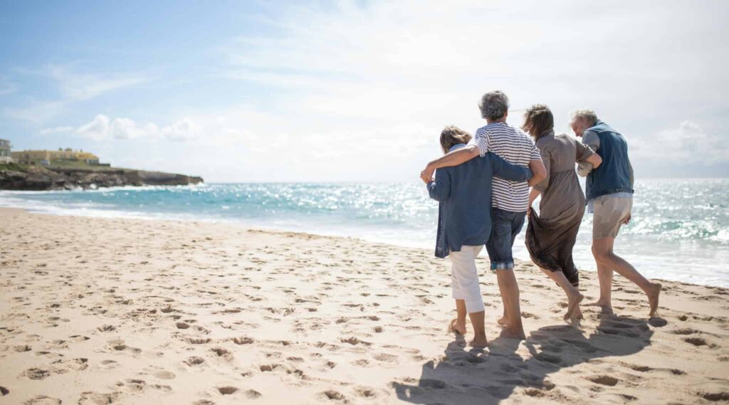 disfruta de tus vacaciones en Huelva | 4 personas caminando por la orilla de la playa en actitud relajada | Grupo Jamsa.